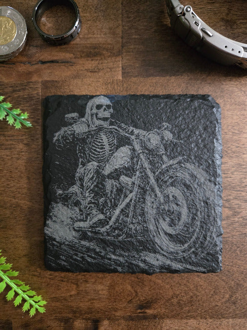 Decorative slate coaster with skeleton design on a wooden surface
