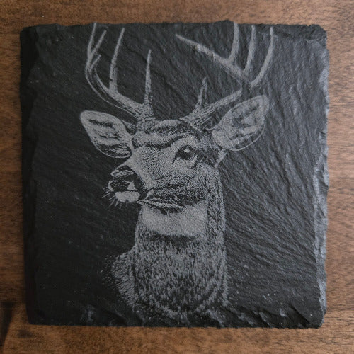 Slate tile with a engraved deer design on a wooden surface