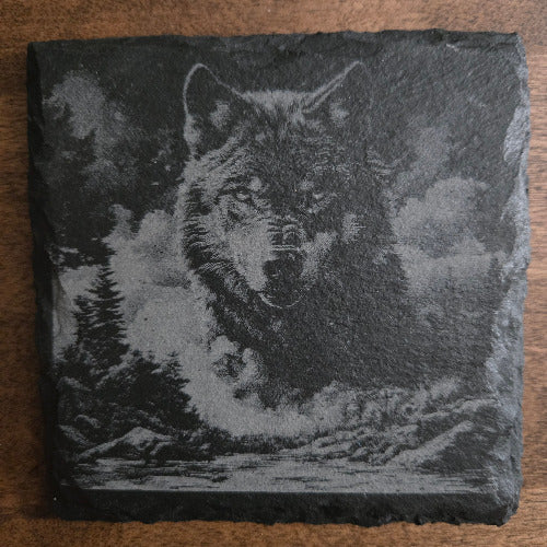 Slate coaster with engraved wolf design on a wooden surface